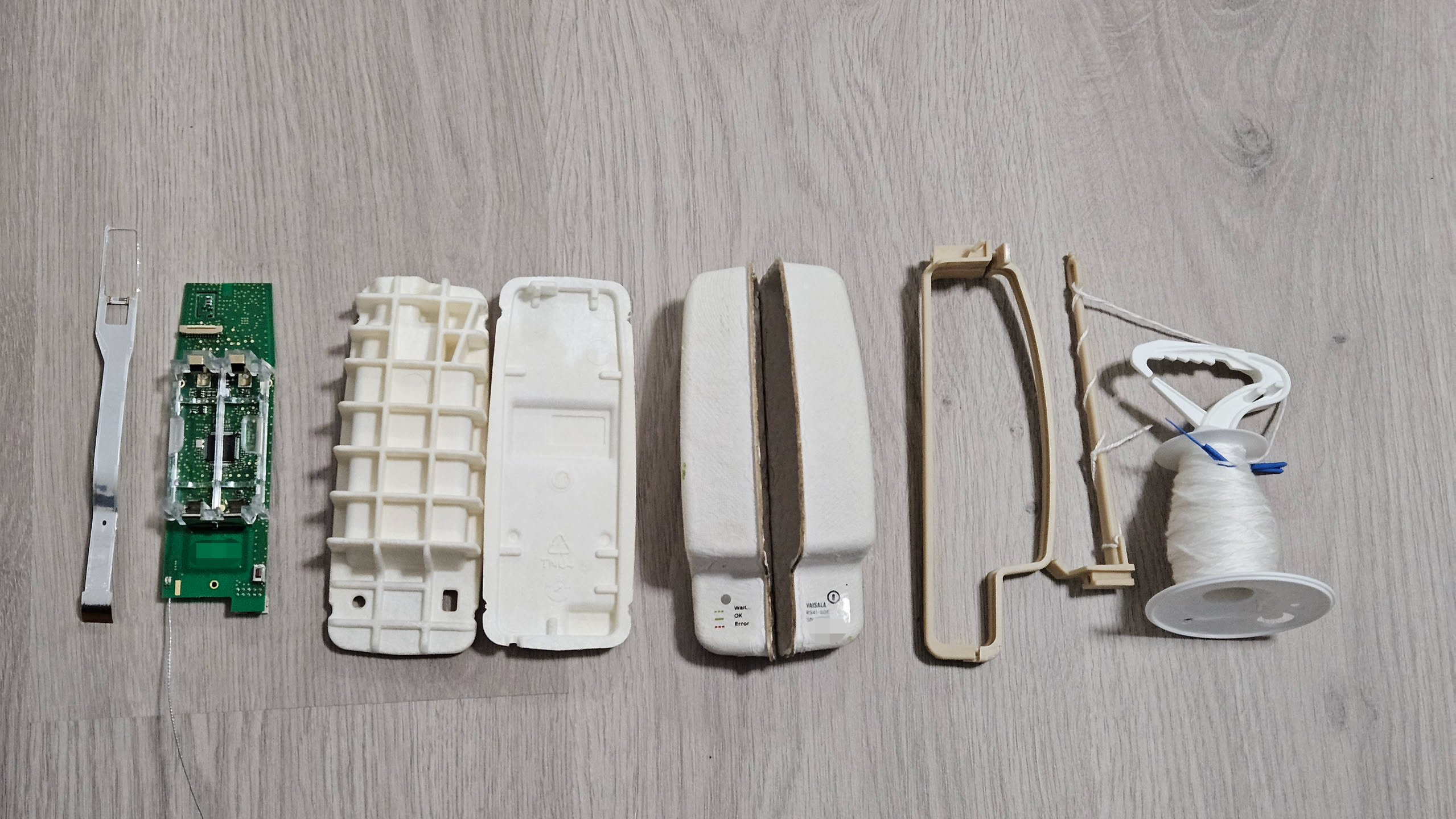 a disassembled radiosonde showing the paper, then foam case, then the pcb